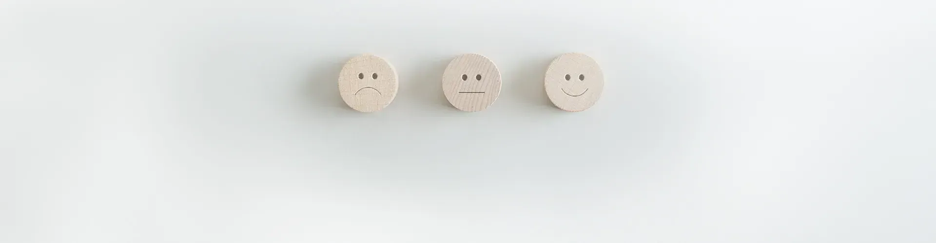Drei Bewertungs-Smileys aus Holz – Feedback zur Pflege von PRICA