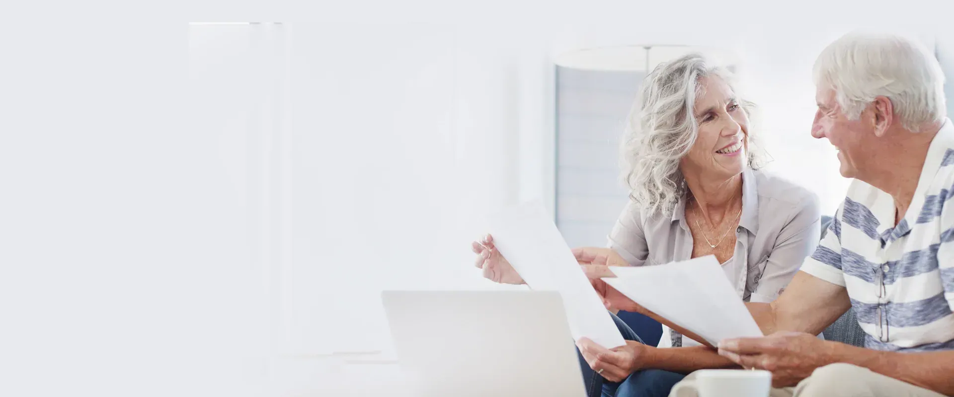 Seniorin prüft Unterlagen zur Pflegefinanzierung am Laptop
